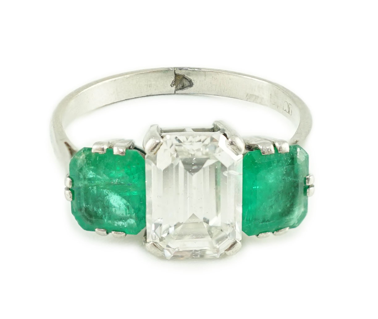 A mid 20th century platinum, single stone emerald cut diamond and two stone emerald set dress ring